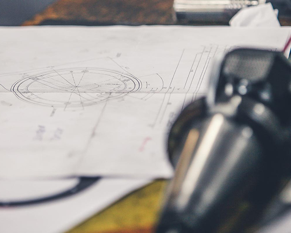 Auf der Werkbank liegt eine technische Zeichnung eines angefertigten Werkstückes. FERTECS GmbH